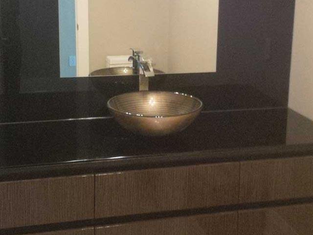 Bathroom sink bowl on brown countertop with brown-framed mirror above