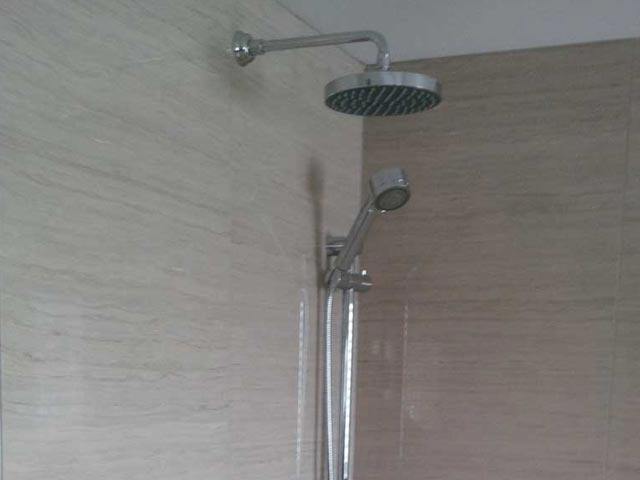 Stand-up shower faucet overhang and handheld faucet unit with beige walls